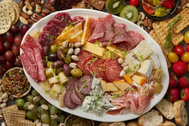 A balanced meal featuring Gouda cheese, whole-grain crackers, and fresh vegetables.