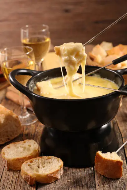 A bubbling pot of Gouda cheese fondue with bread and vegetables for dipping.