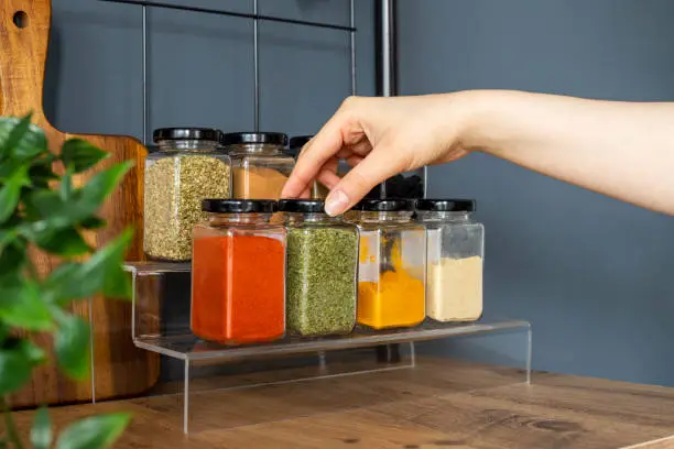 A close-up of dried herb seeds in jars with labels, ready for sale