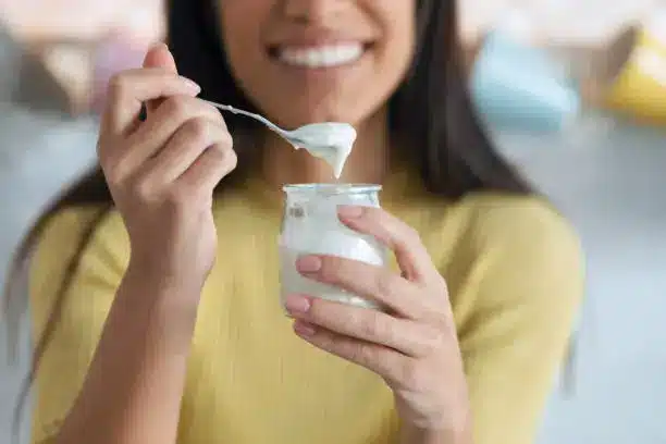 A person enjoying a bowl of yogurt with a smile, symbolizing health and wellness.