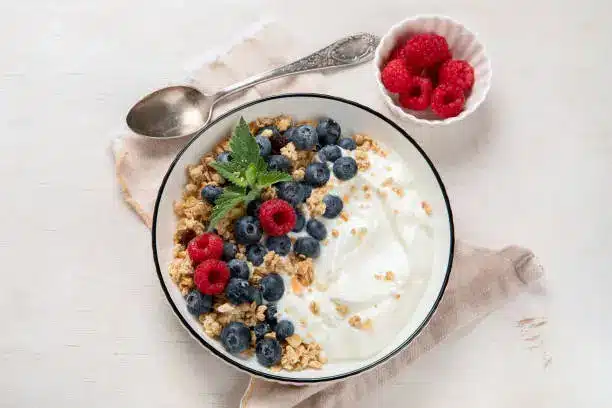 a bowl of creamy yogurt topped with fresh berries and granola.